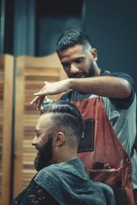 Skilled barber styling a man's hair in a modern barbershop setting, creating a trendy look.