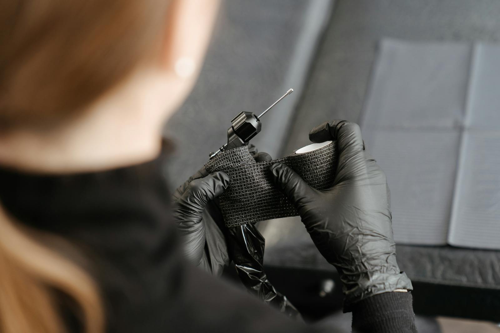 Close-up of a tattoo artist preparing a machine in a professional studio, showcasing the tattooing process.